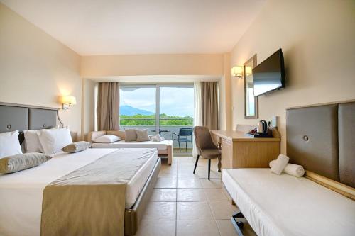 ein Hotelzimmer mit zwei Betten und einem Wohnzimmer in der Unterkunft Cronwell Platamon Resort All-Inclusive in Platamonas