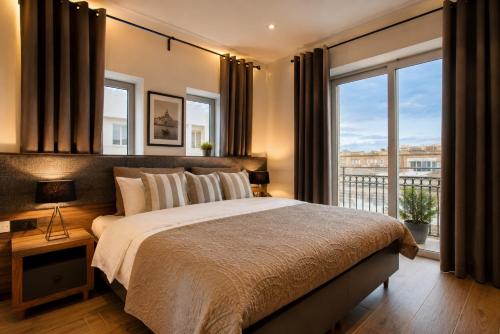 a bedroom with a large bed and a balcony at Tritoni Valletta Boutique Hotel in Il-Furjana