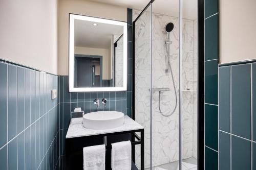 a bathroom with a sink and a shower at Citadines Canal Amsterdam in Amsterdam
