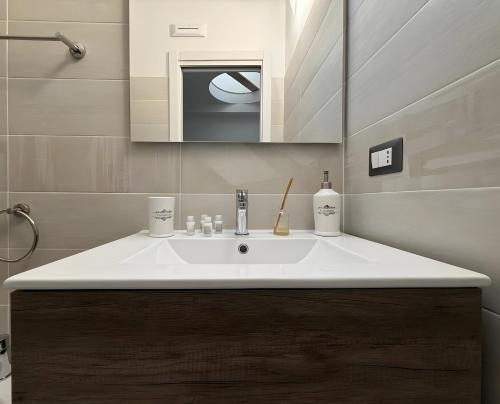 a bathroom with a white sink and a mirror at Maison Vivian Rooms in Marzamemi