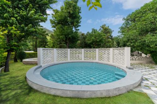 a swimming pool in a garden with a white fence at Emerald Hill Villa by Jodhani in Udaipur