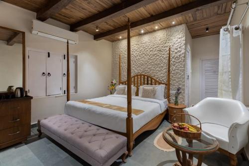 a bedroom with a canopy bed and a chair at Emerald Hill Villa by Jodhani in Udaipur