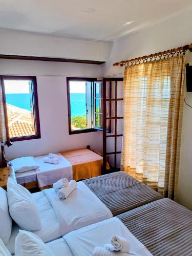 a bedroom with three beds and a view of the ocean at Hotel Erato in Chorefto