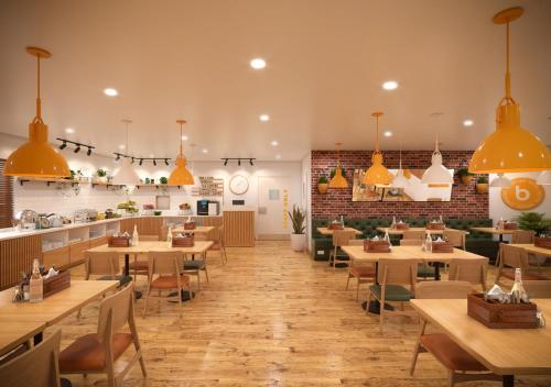 a restaurant with wooden tables and yellow pendant lights at Bloom Hotel Chennai Central in Chennai