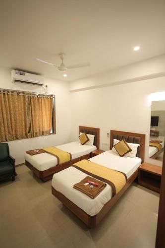 a room with three beds and a window at Hotel Rangoli Dharampur in Dharampur