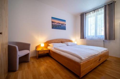 a bedroom with a bed and a chair and a window at Apartment Riviera 503-8 Lipno Home in Lipno nad Vltavou