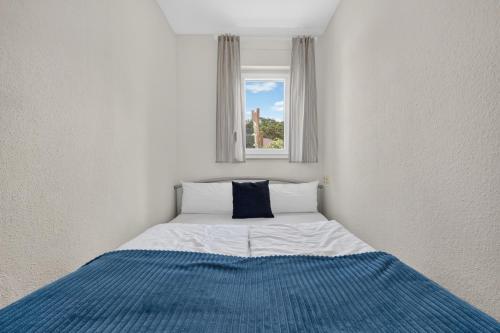 a bed in a white room with a window at Ferienbungalow Malebisa in Loddin