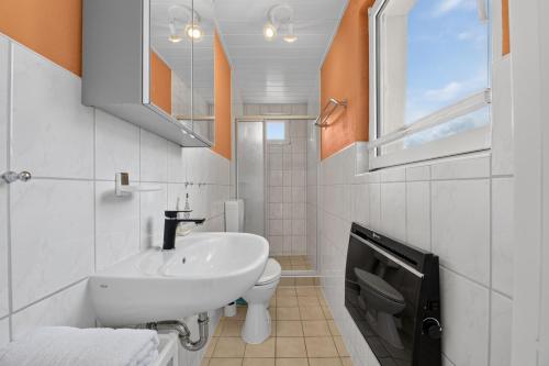 a white bathroom with a sink and a toilet at Ferienbungalow Malebisa in Loddin