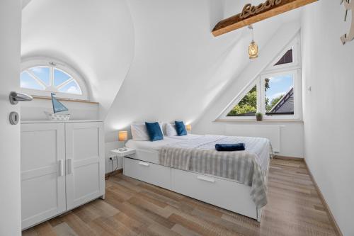 a white bedroom with a bed and a window at Ferienhaus Malebisa in Loddin
