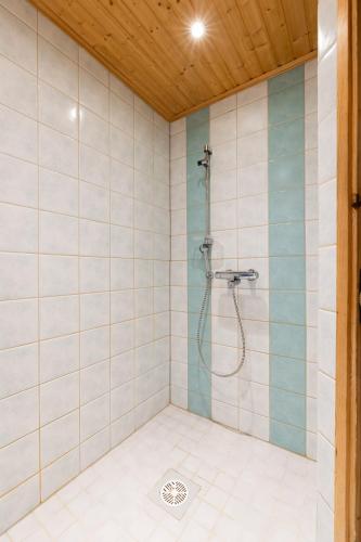 a shower in a bathroom with white tiles at Jehkas Huoneisto B in Kilpisjärvi