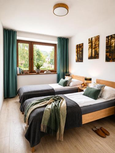 two beds in a room with green curtains at Apartamenty Wisła Krzywa 8, wanna z hydromasażem, basen zewnętrzny in Wisła