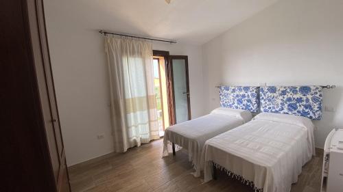 a bedroom with two beds and a window at Stazzo gallurese Li Nibbareddhi in Aglientu