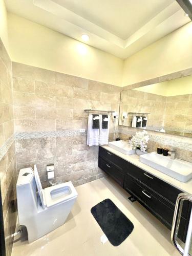 a bathroom with a toilet and two sinks and a mirror at ESEKK Ochi in Ocho Rios