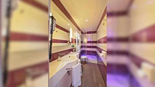a bathroom with a sink and a mirror at The Originals City - Hôtel Saint-Martial, Limoges Centre in Limoges