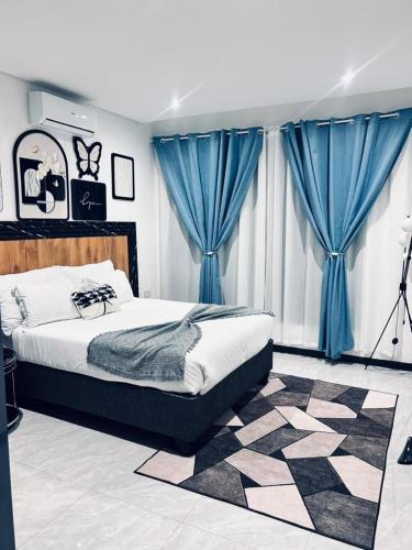a bedroom with a large bed with blue curtains at Platinum apartments in Gaborone