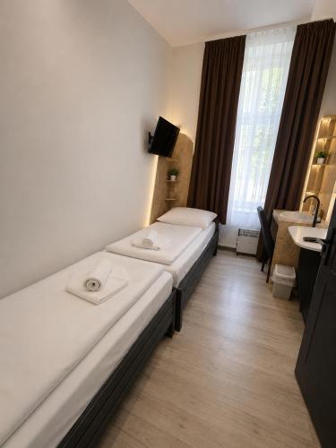 two beds in a small room with a window at Centrum Vendégház in Debrecen