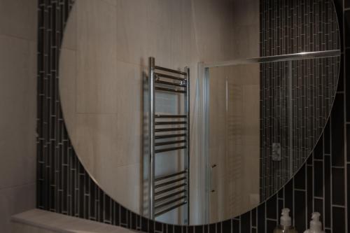 a mirror in a bathroom with a sink and a shower at The Edge Of The Beach in Bude