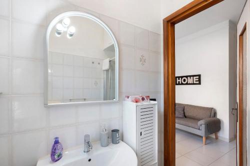 a bathroom with a sink and a mirror and a chair at La Rosa Blu Vacation Home in Sanremo