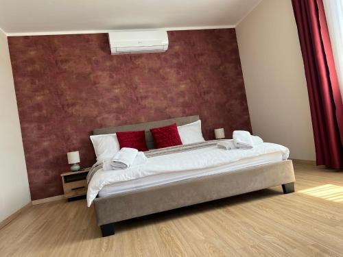 a bedroom with a large bed with red pillows at Kálvária panzió in Tata