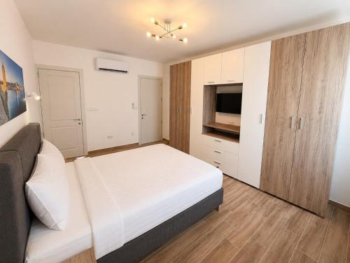 a bedroom with a white bed and a television at Il Kenn ta Zeppi - Apartment 4 in Qala