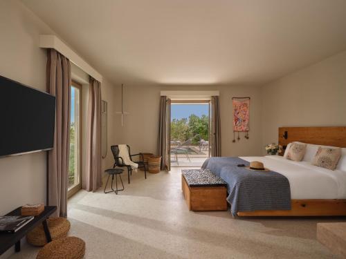 a bedroom with a bed and a television and a table at Noūs Santorini, a Member of Design Hotels in Mesaria