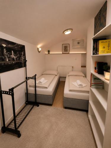a small room with two beds and a book shelf at Centrum Apartman in Debrecen