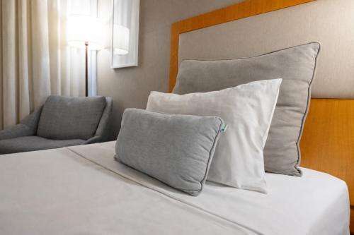 ein Bett mit zwei Kissen und einem Stuhl in einem Zimmer in der Unterkunft Intercity Campinas in Campinas