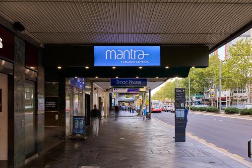 a sign for a store on a sidewalk next to a street at Mantra Adelaide Central in Adelaide