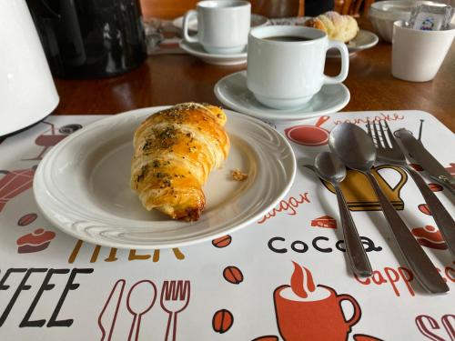 a plate with a pastry on a table with a cup of coffee at Letto Hotel Candeeiro da Serra in São Salvador