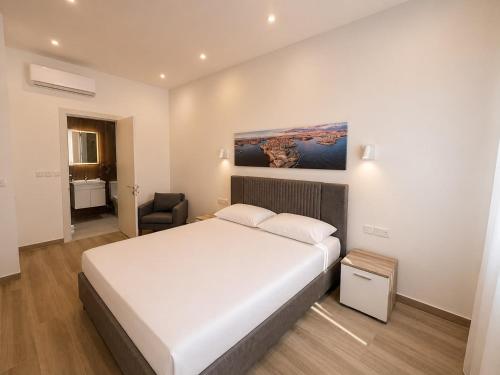 a bedroom with a large white bed and a chair at Il-Kenn ta Roża Maisonette in Qala