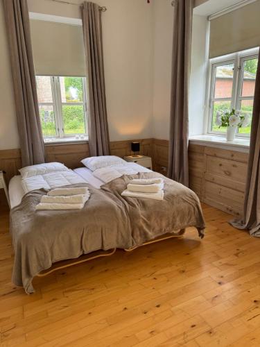 a bedroom with a large bed with two windows at Skelby Præstegård lej 1 in Gedser