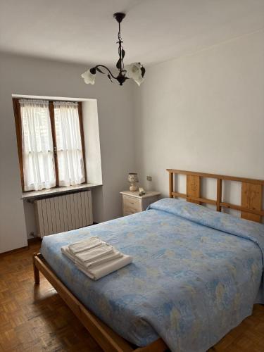 a bedroom with a bed with a blue comforter and two windows at Albergo Nonaj in Monticello d'Alba