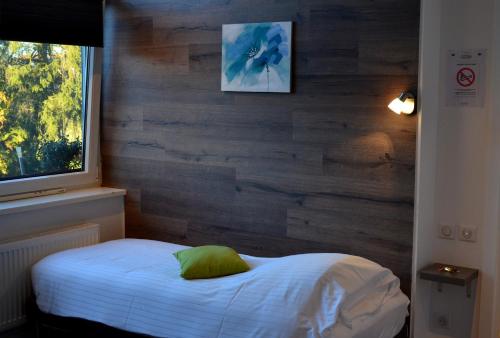 a bedroom with a white bed with a wooden wall at Hôtel Restaurant La Couronne in Roppenheim