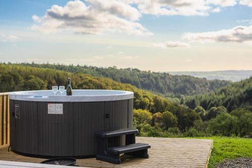 a hot tub on a deck with a view of a forest at Rivendell Farm Glamping in Carmarthen