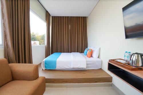 a hotel room with a bed and a chair at SANS Stay Arkana Seturan Pakuwon Mall in Yogyakarta
