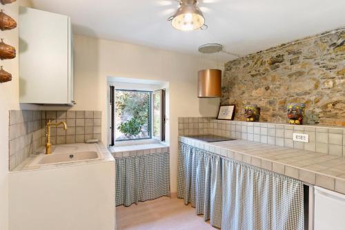 a kitchen with a sink and a stone wall at Pietra Viva in Poggio