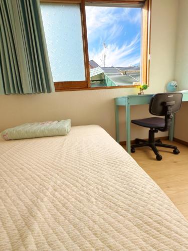 a bedroom with a bed and a desk and a window at Guest House Asahi in Otaru