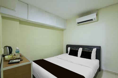 a small room with a bed and a desk with a air conditioner at Collection O Near Taiping Mall Formerly Axis Hotel in Taiping