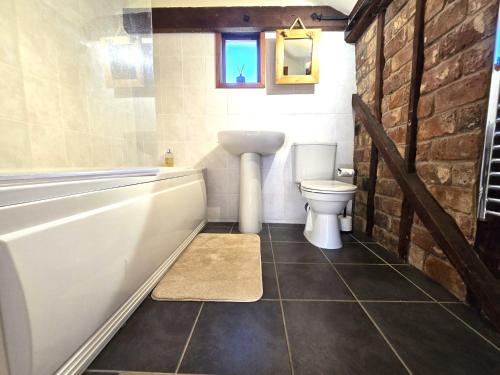 a bathroom with a tub and a toilet and a sink at Barn Conversion Sleeps 2 with Parking in Diss