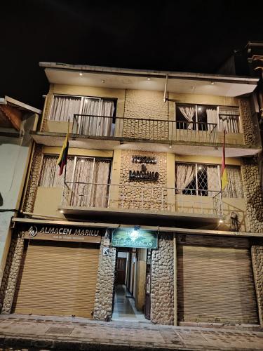 a building with two flags in front of it at Hostal el barranco in Cuenca