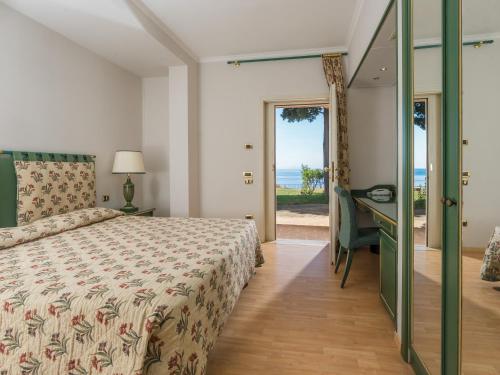 a bedroom with a bed and a desk and a view of the ocean at Altafiumara Resort & Spa in Villa San Giovanni