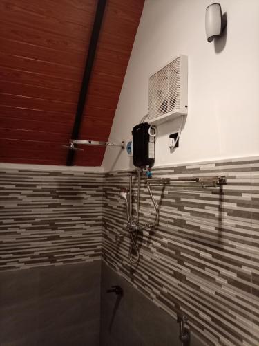 a bathroom with a shower and a fan on the wall at Sunset Dream Cabana in Tangalle