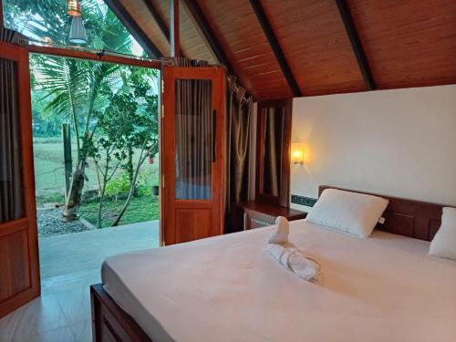 a bedroom with a bed and a large window at Sunset Dream Cabana in Tangalle
