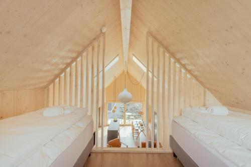 two beds in a room with wooden walls at The Lakehouse in Miðvágur