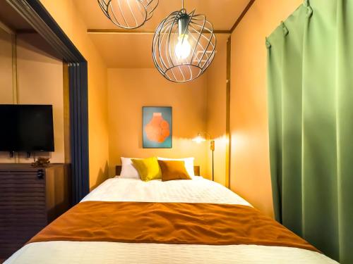 a bedroom with a bed with two lamps and a tv at Meijo Mikan Stay in Nagoya