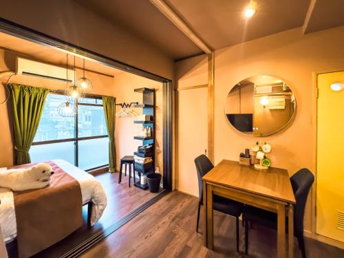 a room with a bed and a table and a mirror at Meijo Mikan Stay in Nagoya