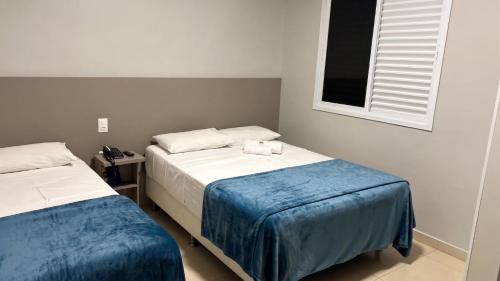 a bedroom with two beds with blue sheets and a window at Ribs Hotel in Piauí
