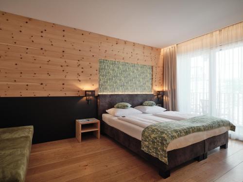 a bedroom with a large bed and a wooden wall at Cityhotel Goldener Adler B&B in Chiusa