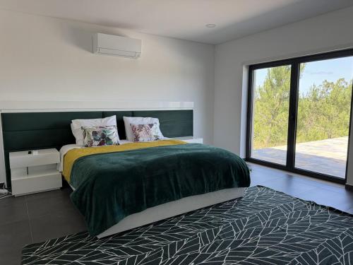 a bedroom with a bed and a large window at Casa na Colina - Private Pool & Jacuzzi in Santiago da Guarda