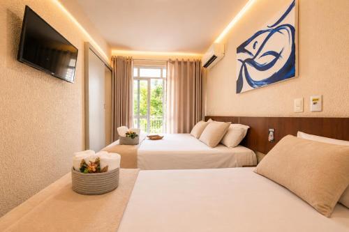 a hotel room with two beds and a tv at Hotel Rotorua inn Fortaleza - Beira Mar in Fortaleza